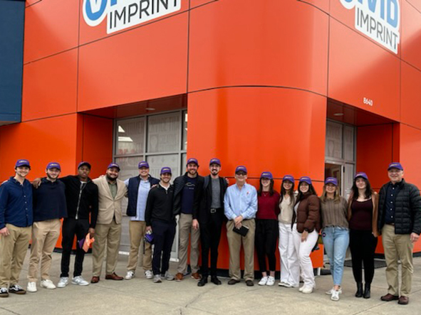Group of students in purple caps stand outside Vivid Ink in Baton Rouge, this was part of the December 2023 LEEPS trip.