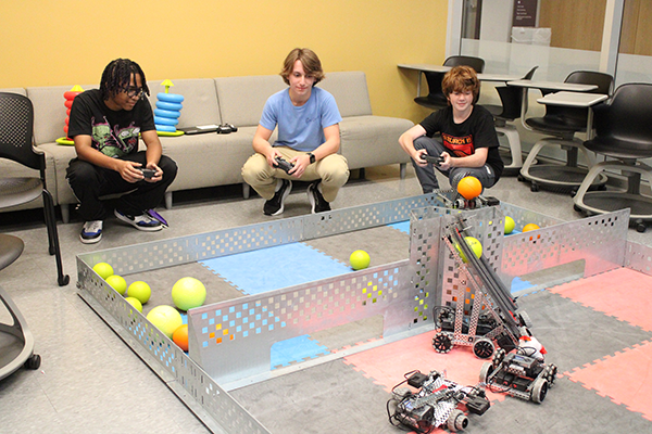 Three students controlling their robot