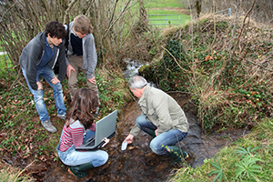 Photo of students recording samples taken from a stream.